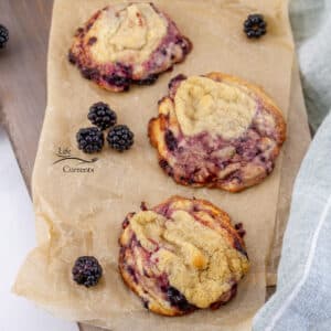 looking down on three blackberry cookies on a piece of parchment paper.