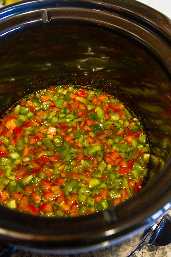 looking in the bowl of a crock pot that's filled with chopped peppers.