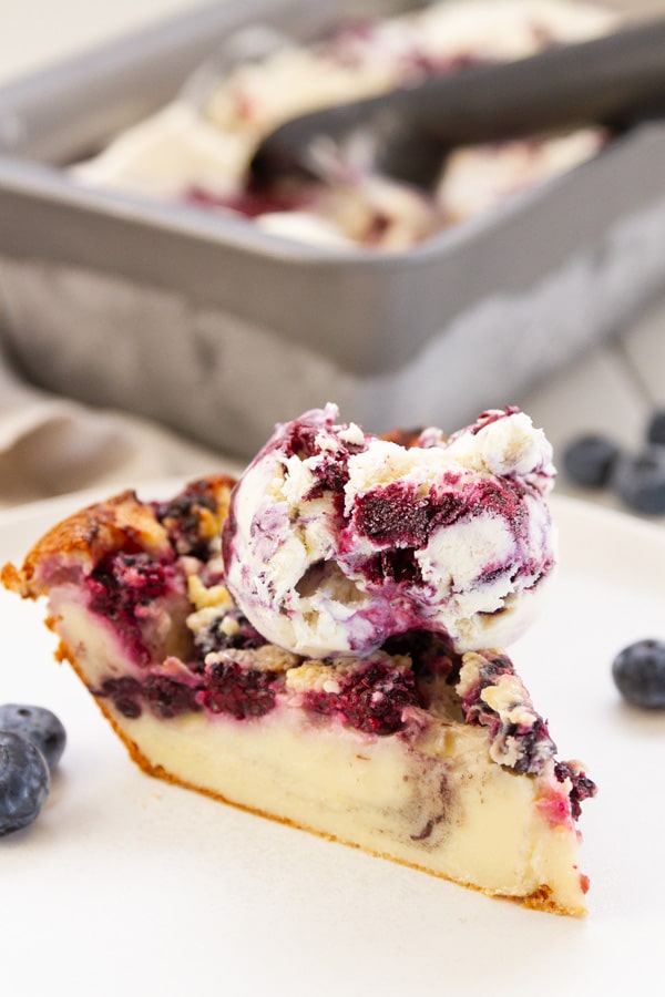 a slice of blackberry pie served with blueberry ice cream in front of the ice cream dish.