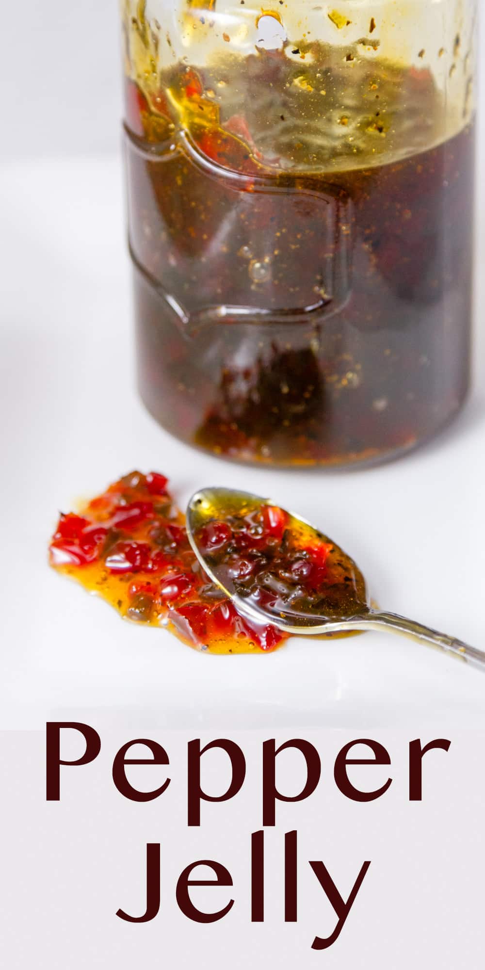 a mason jar filled with pepper jelly and a spoon in front has drizzled some jelly out.