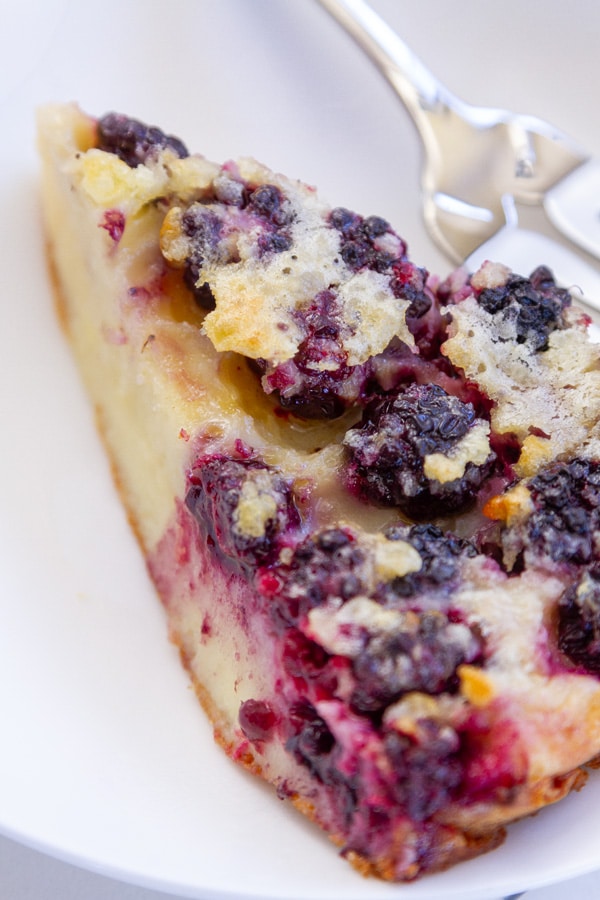 a slice of pie with blackberries in it and a fork next to it.