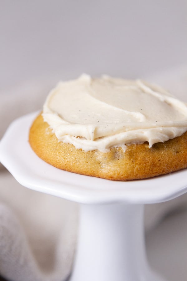 a frosted cookie on a small white pedestal.