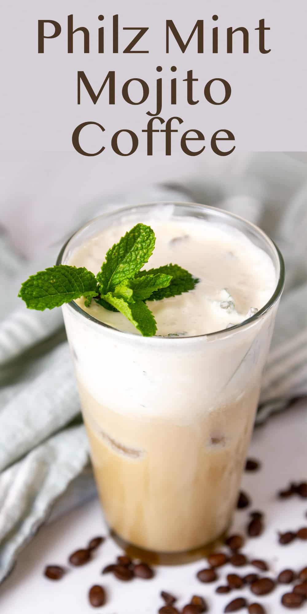 a glass of iced coffee topped with cold foam and a mint sprig.