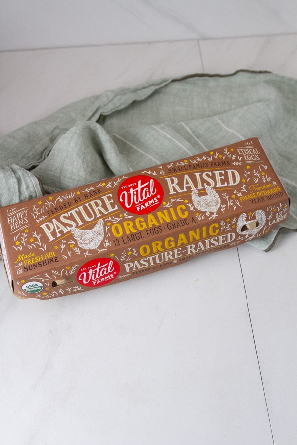 a carton of eggs next to a green cloth towel.