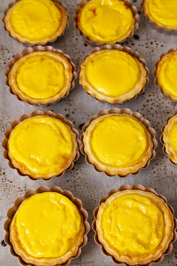 tarts on a baking sheet still in their tart pans.