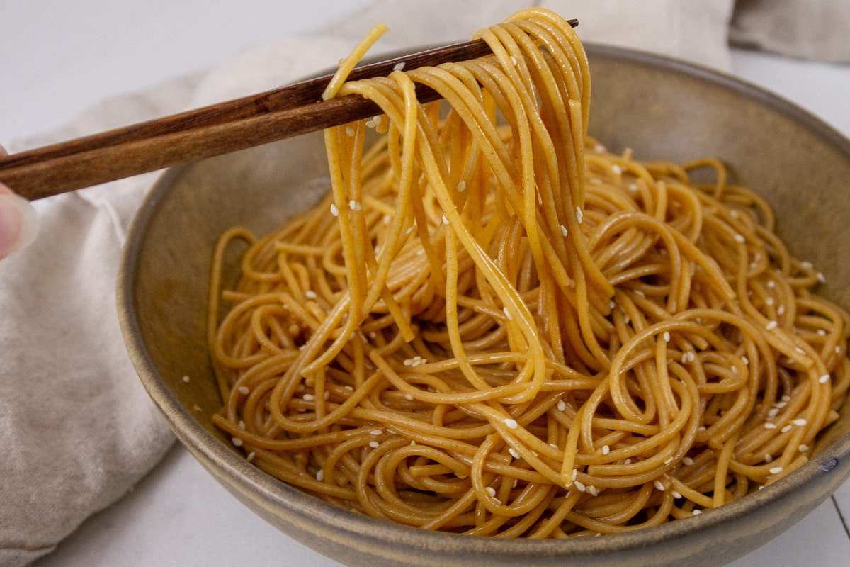 noodles being picked up by chopsticks.