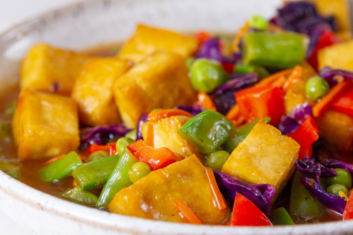 orange peel tofu with veggies in a white bowl.