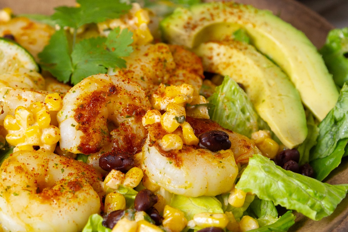 seared and spiced shrimp with corn black beans and avocados over lettuce.