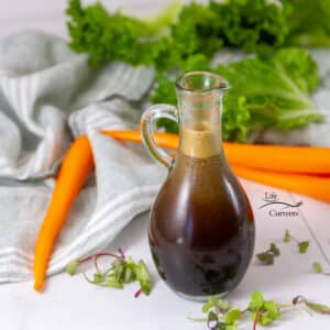 square crop of a bottle of Soy Vinaigrette Dressing in front of some veggies and a cloth napkin.