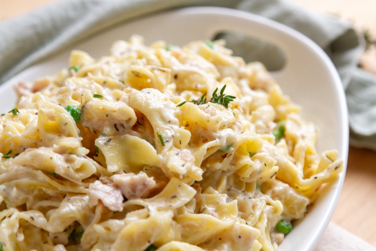 tuna noodle casserole in a white serving platter with a green cloth napkin in the background.