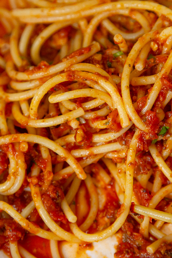 a close up on noodles covered with red meatless meat sauce and some fresh basil garnish.