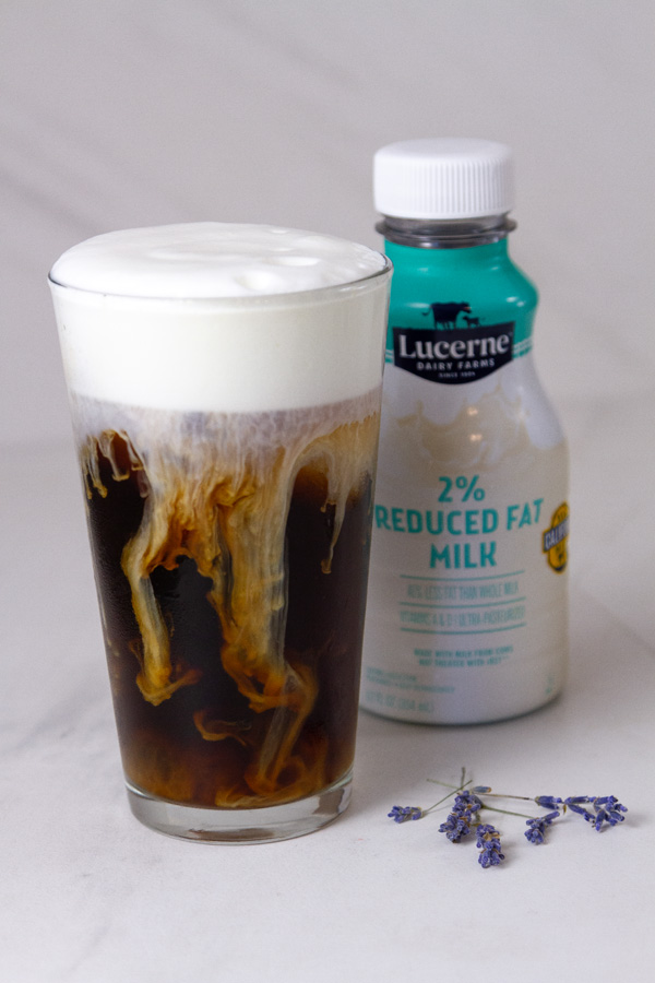 an iced coffee made with 2% milk and the bottle of milk is in the background.