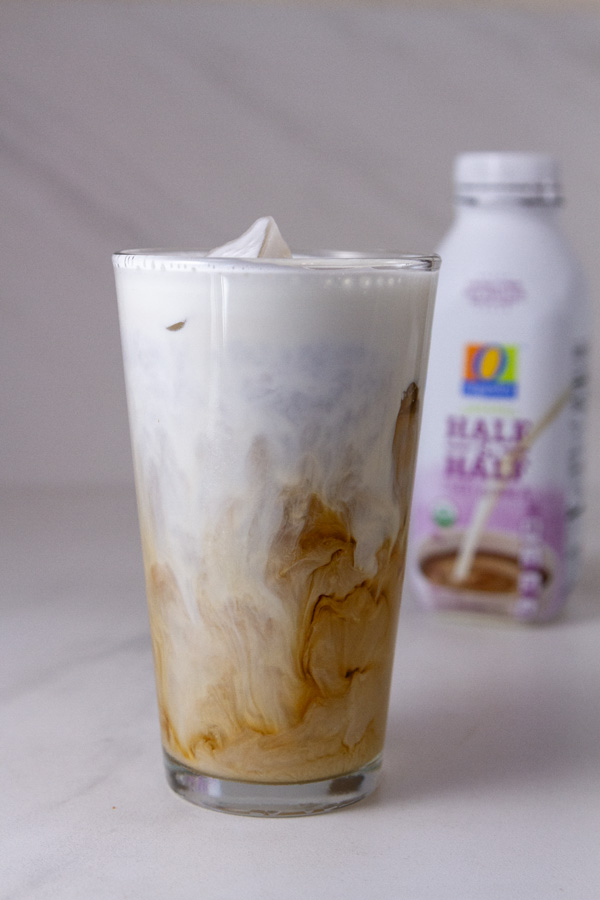 an iced coffee made with half and half nad the bottle of half and half is in the background.
