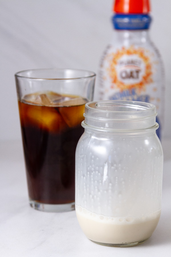 an iced coffee, a mason jar, and a bottle of creamer in the background.
