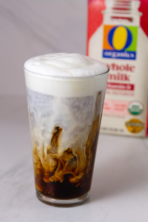 an iced coffee made with whole milk and the carton of milk is in the background.