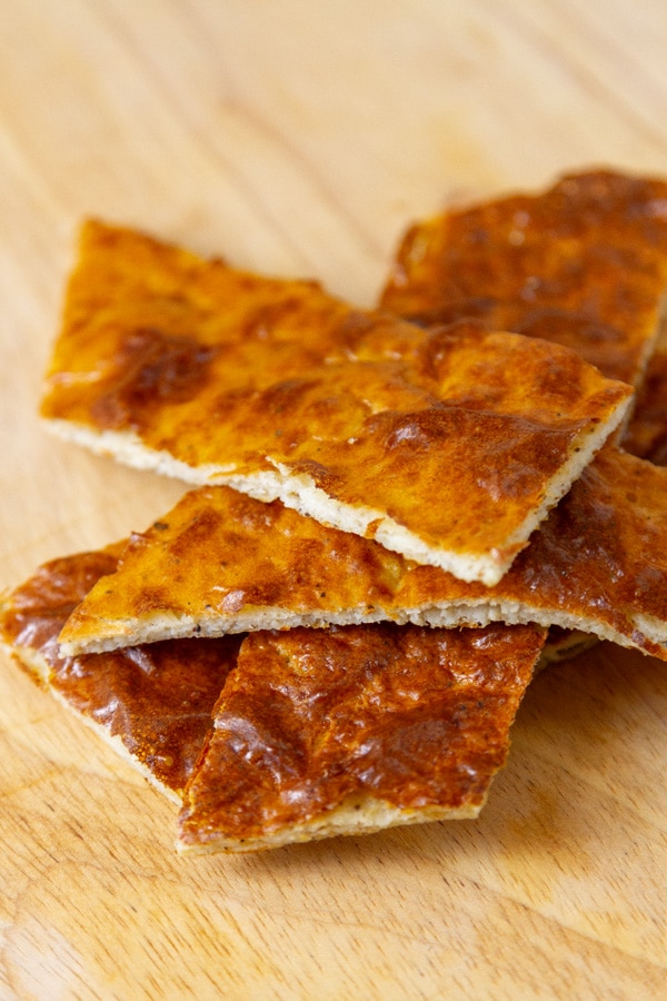 small slices of flatbread made with cottage cheese in a pile on a wooden cutting board.