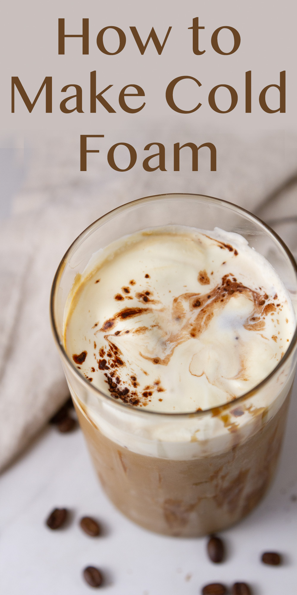 Looking down into a glass of iced coffee topped with cold foam and garnished with cocoa powder.