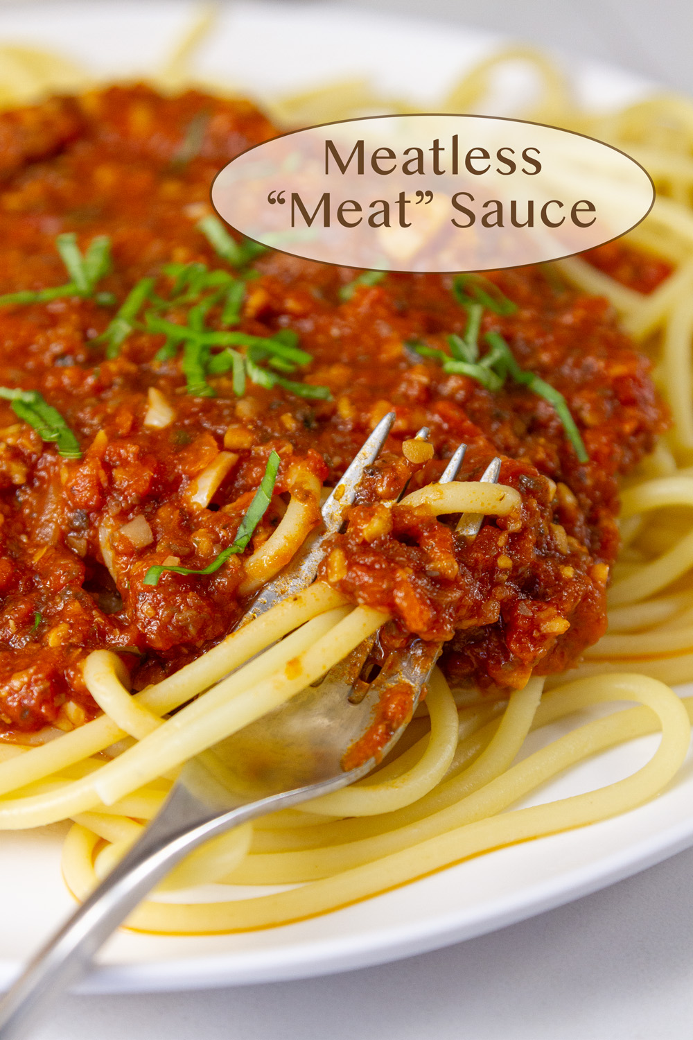 a white plate with pasta and meatless meat sauce on the pasta with a fork in the pasta.
