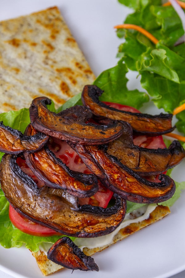 a BLT sandwich made with mushroom bacon on cottage cheese bread with a green salad on the side.