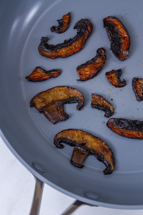 pieces of mushrooms in a grey skillet.