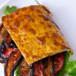 square crop of cottage cheese bread surrounding sandwich fillings of mushrooms, lettuce, tomato.
