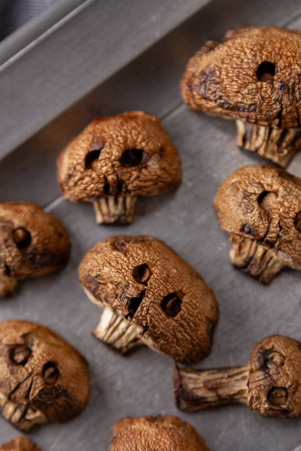 brown mushrooms carved to look like skulls on a pewter tray.