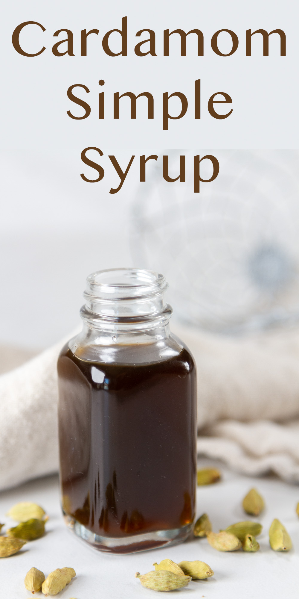 a small bottle with simple syrup in it with a napkin and cardamom pods around it.