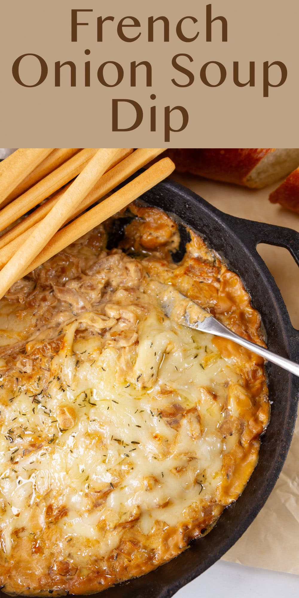 looking down into a skillet filled with onion and cheese dip and some breadsticks on the side of the skillet.