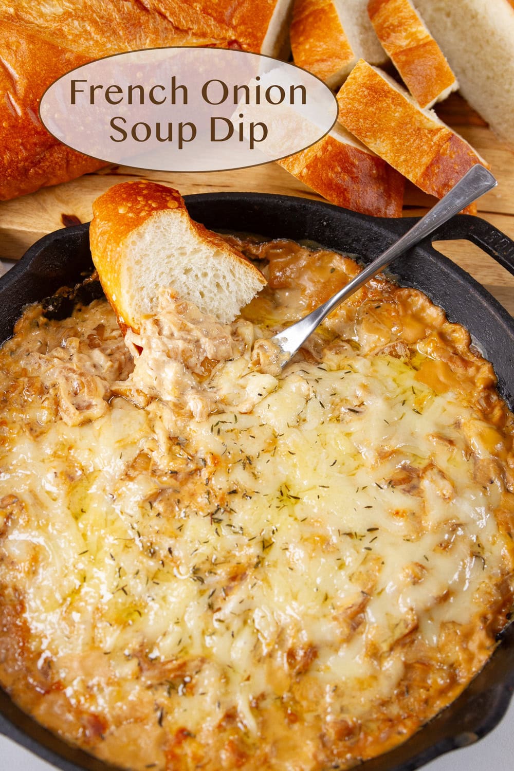 A cast iron skillet with cheesy dip in it bread around the outside of the skillet and a knife in the dip.