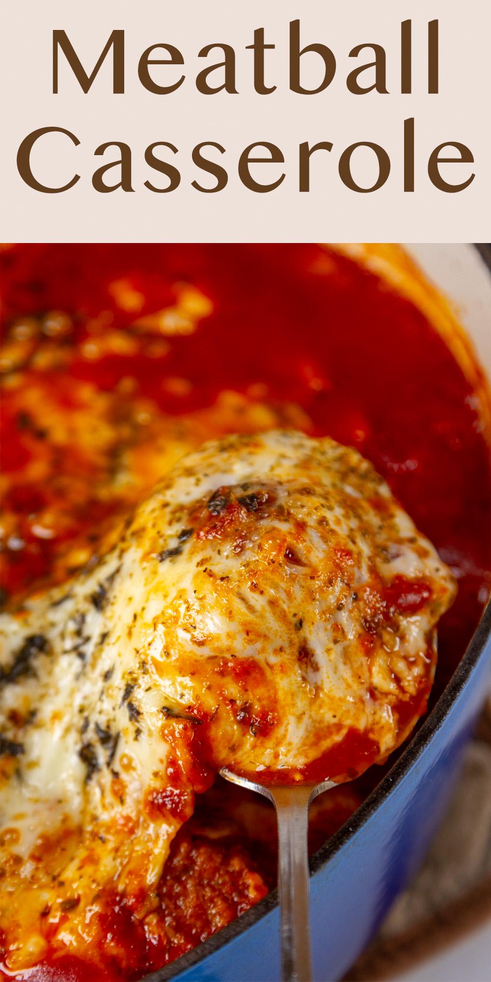 a meatball covered in pasta sauce and cheese being taken out of a blue casserole dish.