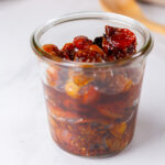 square crop of a glass jar filled with cooked tomatoes in juice.