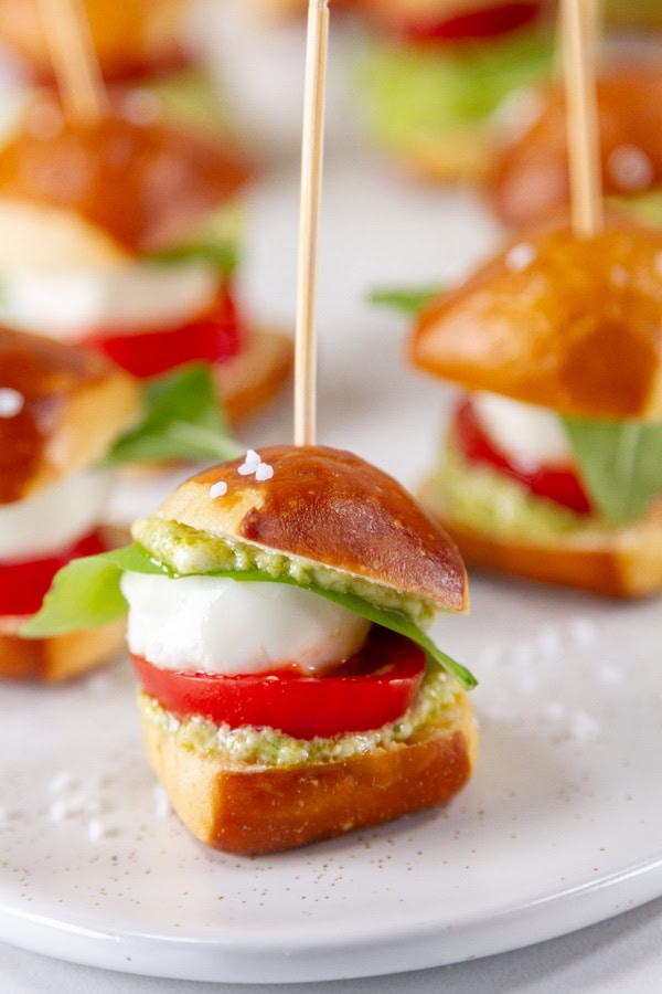 Caprese sandwich on mini pretzel bites with a toothpick in it.