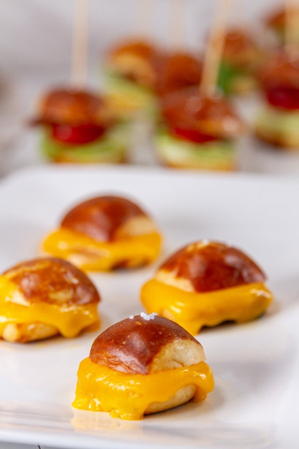 grilled cheese pretzel bites in front of BLT and Caprese bites on white trays.