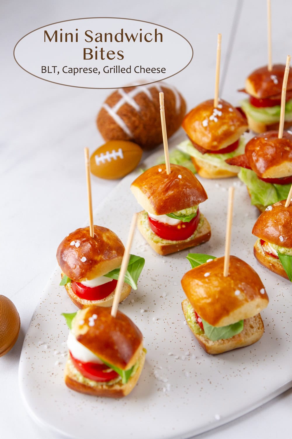 Mini Sandwich bites with toothpicks in them on a white serving platter.
