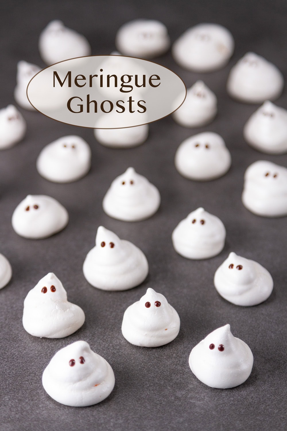 many meringue ghosts on a dark gray background.
