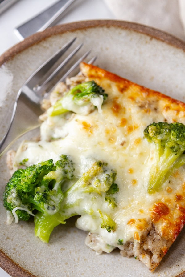 a serving of cheesy rice casserole on a plate with a fork.