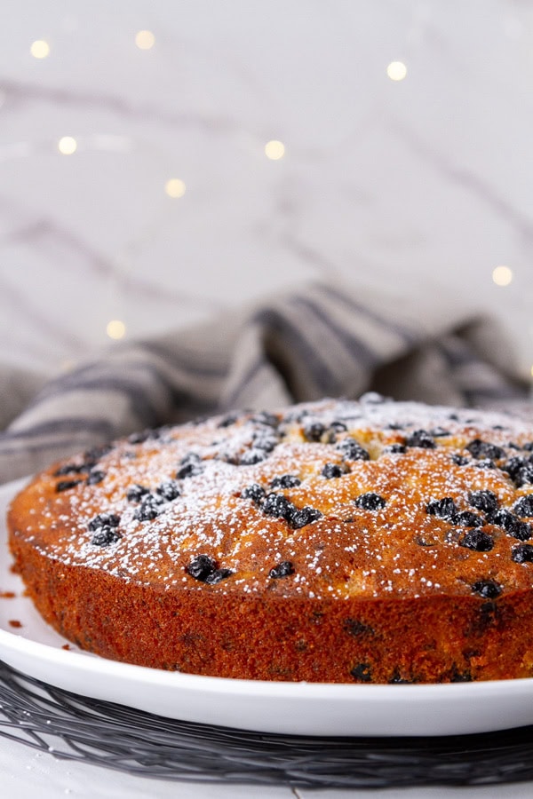 cake on a white plate in front of twinkle lights.