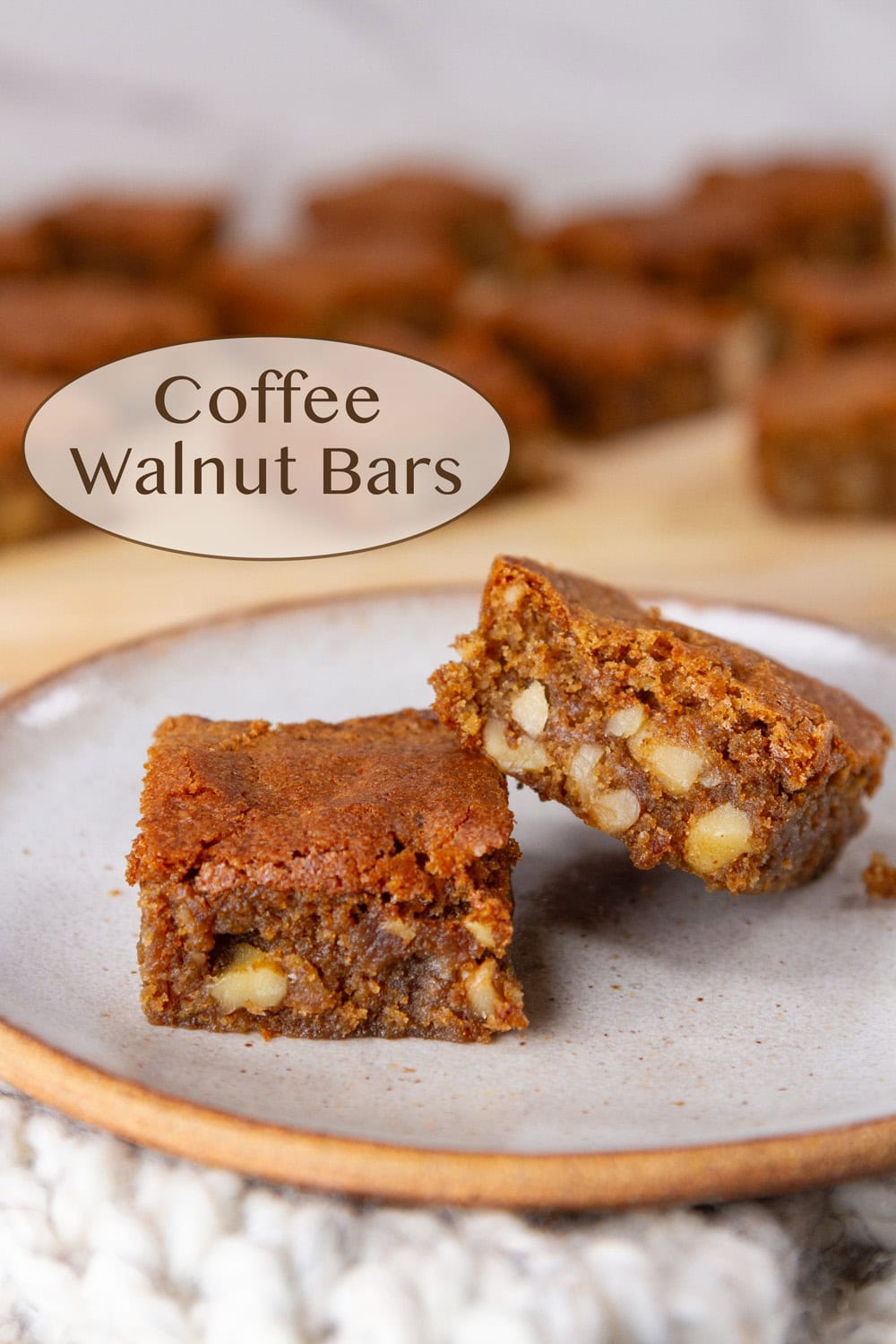Two coffee walnut bars on a plate in front of the rest of the cookies.