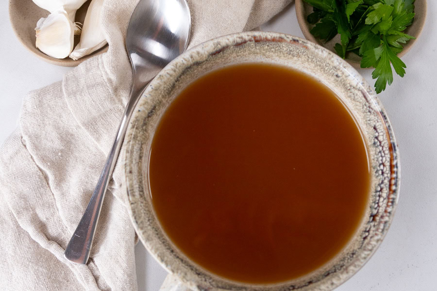 looking down into a cup of soup with a spoon off to the upper left.