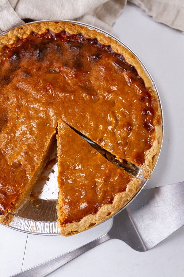 A pie with a slice taken out and a pie server next to it.