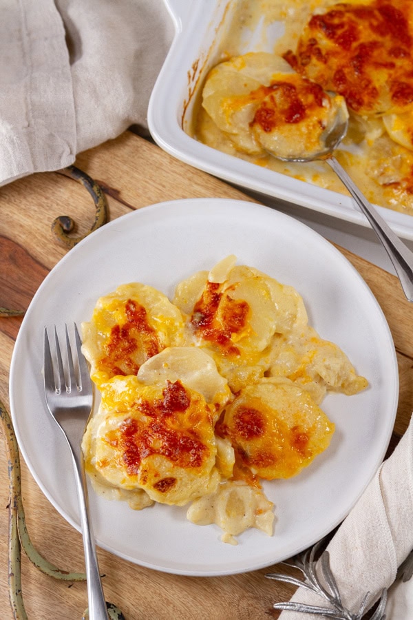 looking down on a serving of potatoes au gratin next to the casserole dish.