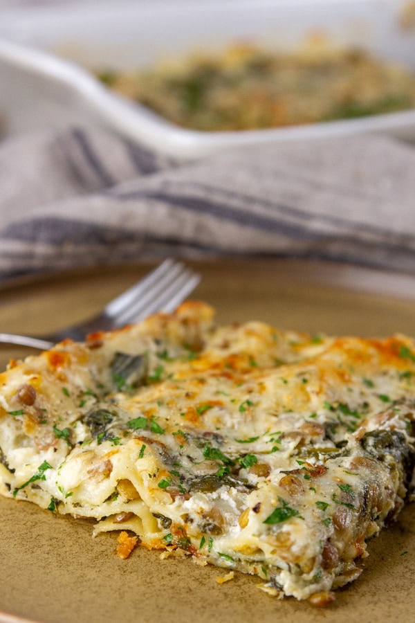 a slice of lasagna with a fork next to it on a brown plate.