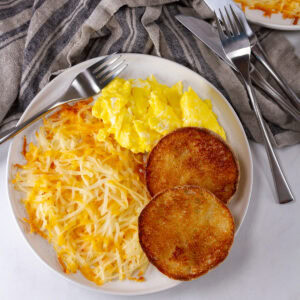 square crop of a plate of breakfast with hash browns, eggs, and English muffin.