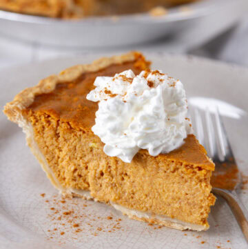 square crop of a slice of pumpkin pie on a plate with a fork.
