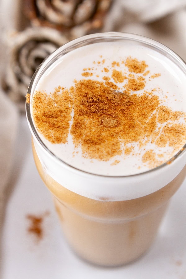 a gingerbread latte topped with cold foam and gingerbread spice with Christmas decorations in the background.