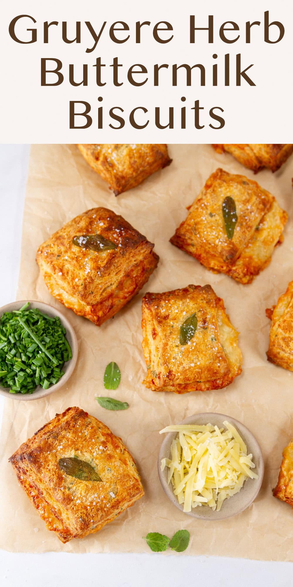 some biscuits on parchment paper with a small dish of shredded cheese and another of chopped chives.