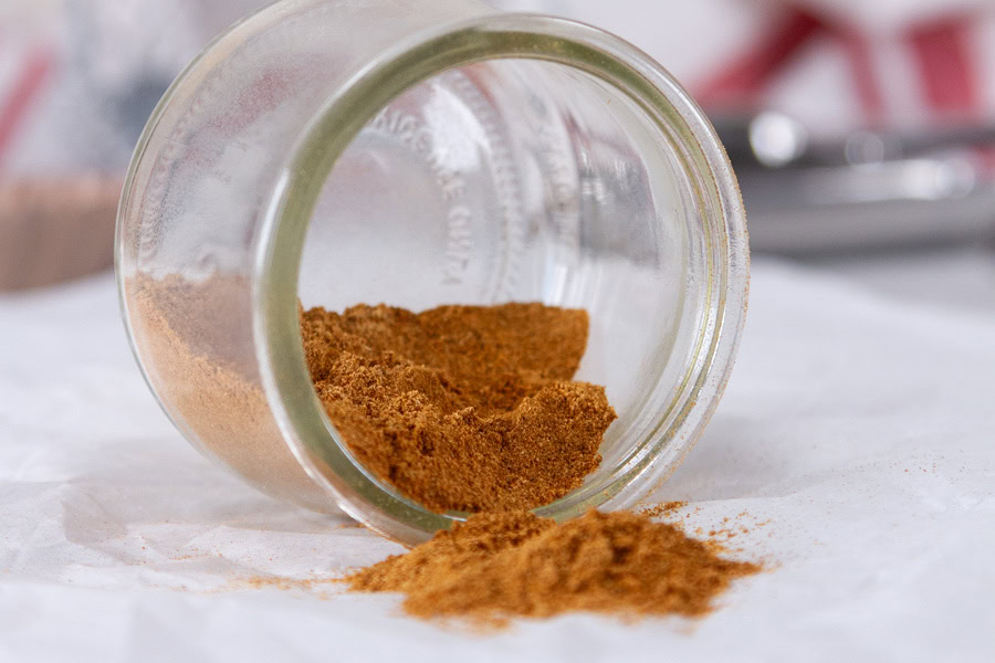 horizontal crop of a glass jar that's tipped over to show the spice inside.