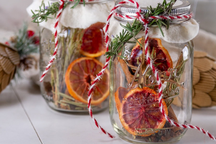 two mason jars wrapped up to loo festive next to paper pine cones.