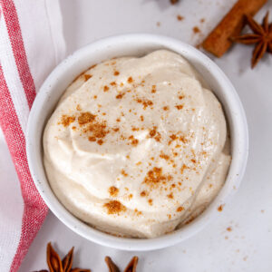 square crop looking down into a cup of gingerbread pudding topped with gingerbread spice mix and a red striped towel in the background.