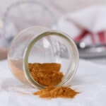 square crop of a glass jar of gingerbread spice mix that's tipped over so you can see the spice.